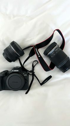 a camera and lens sitting on top of a white sheet with the strap attached to it