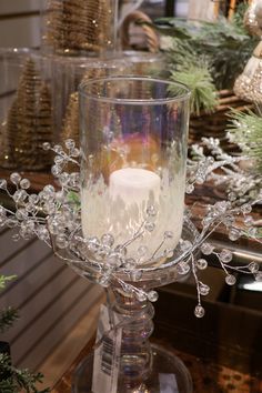 a clear glass candle holder sitting on top of a table next to christmas trees and ornaments