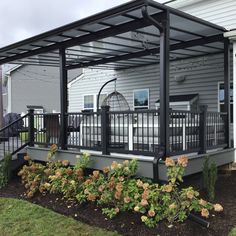 a house with a metal roof and railings on the front porch, surrounded by flowers