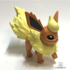 a yellow toy with black eyes and wings on it's back legs is standing in front of a white background