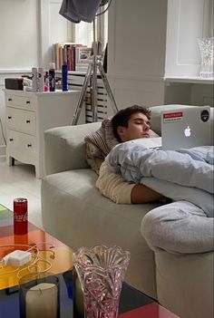 a man is laying on the couch with his laptop in front of him while he sleeps