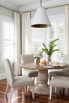 a dining room table with four chairs and a bowl of oranges on the table