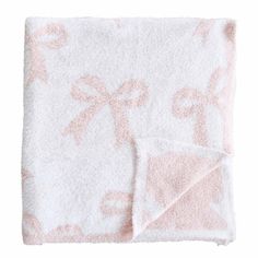 the pink and white blanket is folded on top of it's own, with an embroidered design