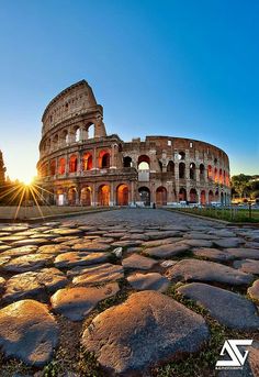 the colossion in rome, italy at sunset with bright sun rays coming through