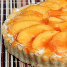 a pie with peaches on top sitting on a cooling rack