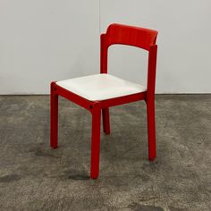 a red and white chair sitting on top of a cement floor