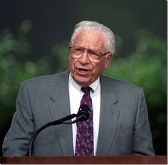 an older man in a suit and tie speaking at a podium