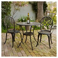 an outdoor table with two chairs and a bottle of wine