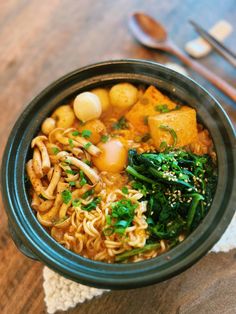 a bowl of ramen with broccoli and tofu in it next to chopsticks