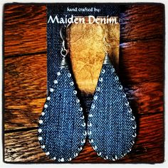 two pairs of denim earrings on top of a wooden table with the words maden denim written