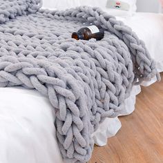 a blanket that is on top of a bed with a beer bottle laying on it