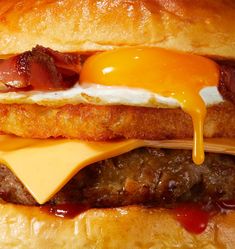 a hamburger with bacon, cheese and an egg on the bun is shown in close up