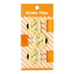 two yellow and white hair clips with faces on them in front of an orange striped background