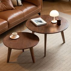 two wooden tables sitting on top of a carpeted floor next to a brown couch