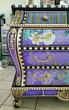 an elaborately painted chest of drawers on display in a store or showroom,