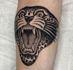 a black and white tattoo of a tiger on the right leg with its mouth open