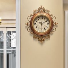 a gold clock mounted to the side of a wall next to a doorway with glass doors