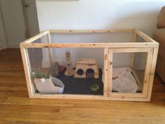 a small caged area with toys in it on top of the wooden floor next to a couch