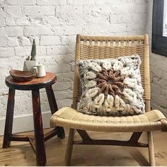 a chair with a pillow on it next to a small table and potted plant