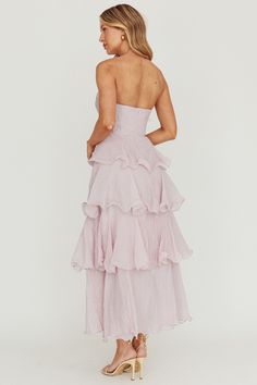 a woman in a strapless dress with ruffles on the skirt and heels