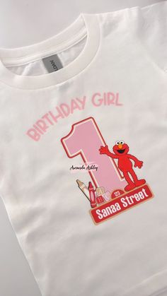 a white birthday shirt with the number one on it and an image of sesame street