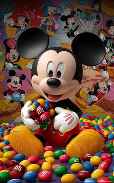 the mickey mouse is sitting in front of many candy candies and other disney characters