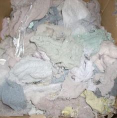 a cardboard box filled with lots of different colored cloths and other things in it