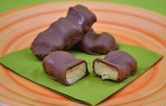 three pieces of chocolate on a plate with green napkin and orange stripe around the edge