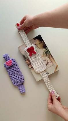 two crocheted objects are being held by someone's hand on a table