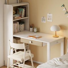 a white desk and chair in a small room with a book shelf on the wall