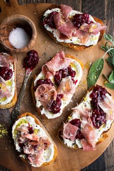 bread topped with meat and cranberry sauce on top of a wooden cutting board