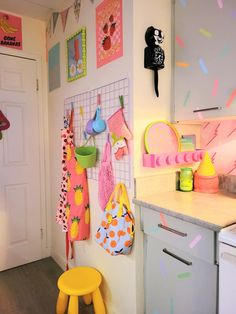 a kitchen area with various items hanging on the wall and a yellow stool in front of it