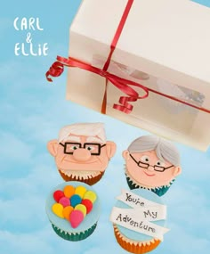 two cupcakes in the shape of an elderly couple under a gift box