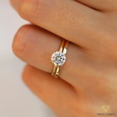 a woman's hand holding a ring with a diamond on it and the band is yellow gold