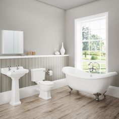 a white bath tub sitting next to a toilet and sink in a bathroom under a window