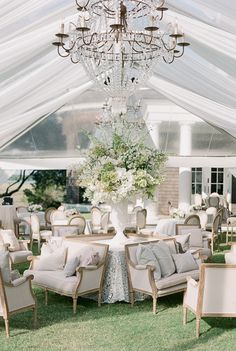 an outdoor wedding reception setup with chandelier and chairs