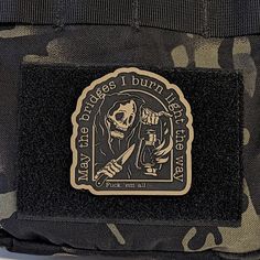 a patch on the back of a camo bag with a skeleton holding a knife