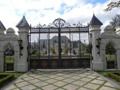 an iron gate is in front of a white fence with black gates on both sides