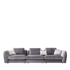 a gray couch with pillows on it and a white wall in the backround