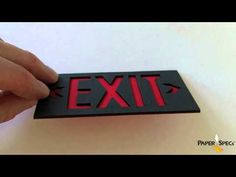 a hand is holding an exit sign with red letters on the front and back side