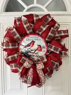 a red and white christmas wreath with two birds hanging from it's front door