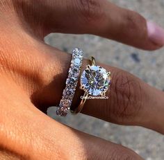 a woman's hand with two rings on it and one has a diamond in the middle