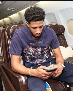 a man sitting on an airplane looking at his cell phone