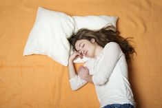 a woman laying on top of a bed next to a pillow