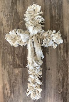 a cross made out of torn fabric on a wooden floor