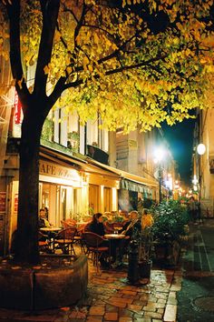 an empty street at night with tables and chairs