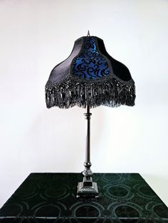 a lamp that is sitting on top of a table with a blue and black shade