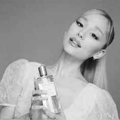 a black and white photo of a woman holding a perfume bottle