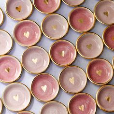 many pink and gold plates with hearts are arranged on a white table top, in rows