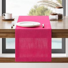 a pink table runner with a white plate on it